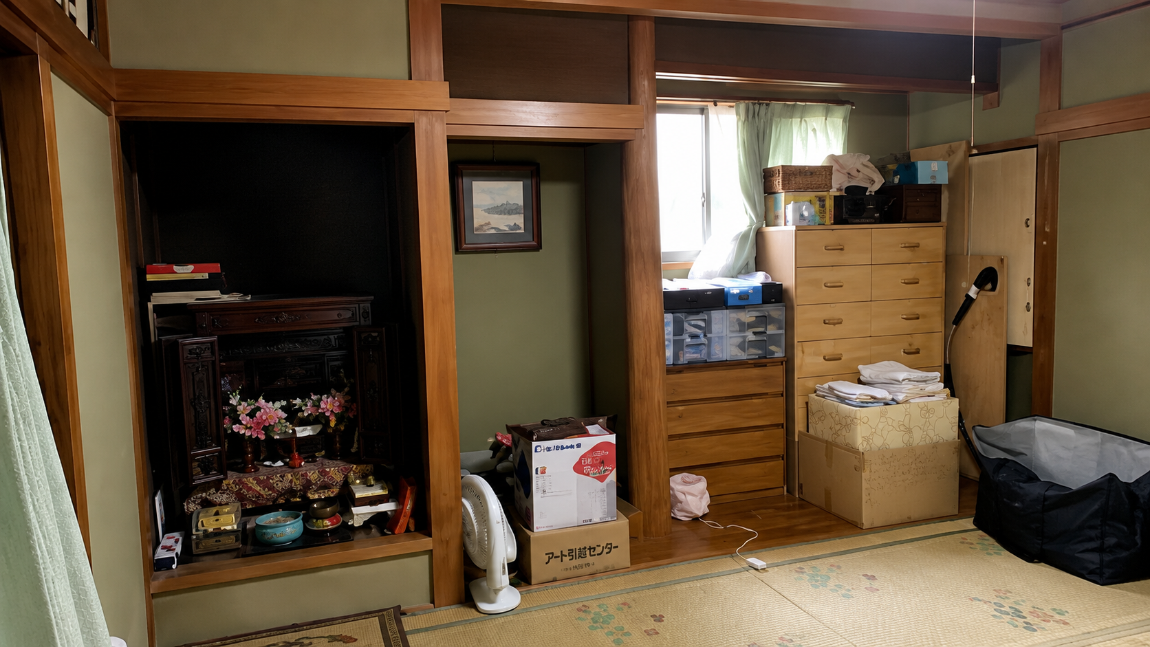 Traditional Japanese-style room with a wooden alcove containing a small home altar, and a cluttered dresser, boxes, and fan on tatami mats