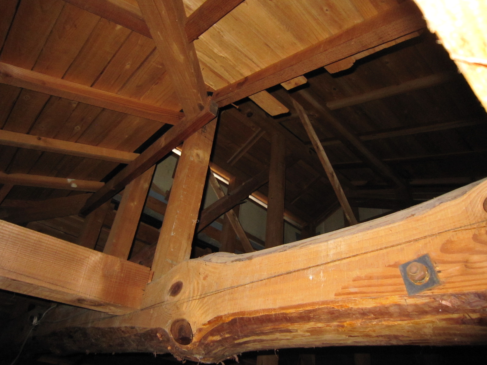 Attic with exposed wooden beams and diagonal braces forming roof trusses