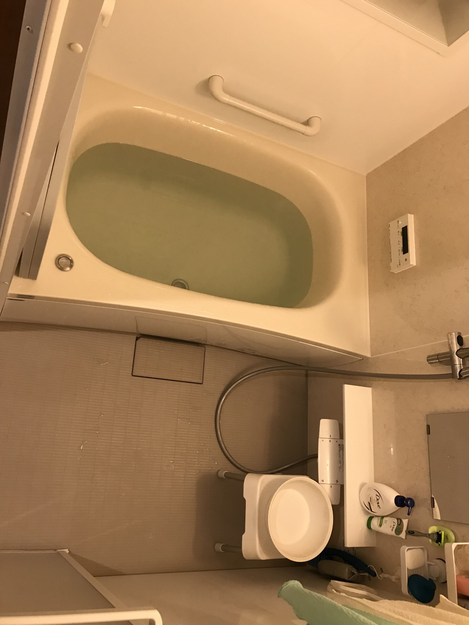 Small bathroom with a white bathtub, a horizontal grab bar on the wall, and toiletries on the counter nearby.
